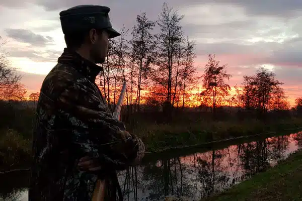 Jäger mit gewehr im sonnenuntergang